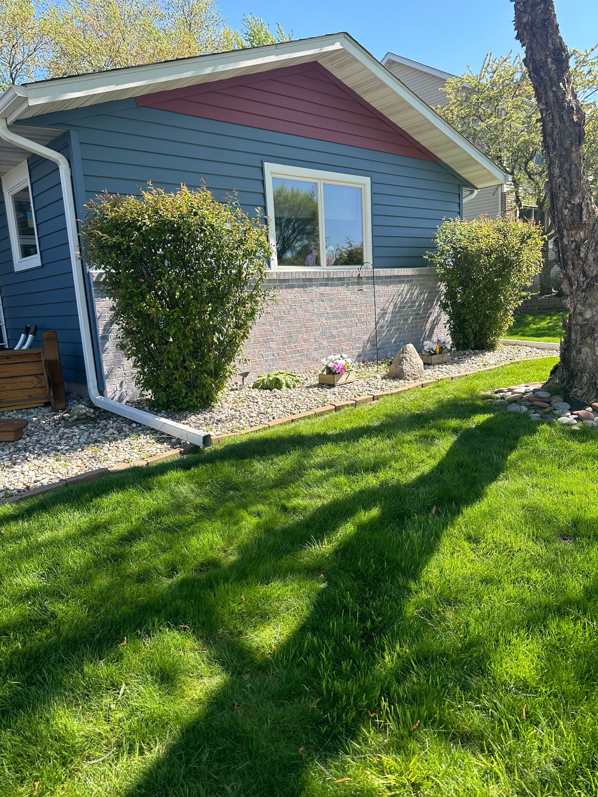 A blue house with a red roof is sitting on top of a lush green lawn.