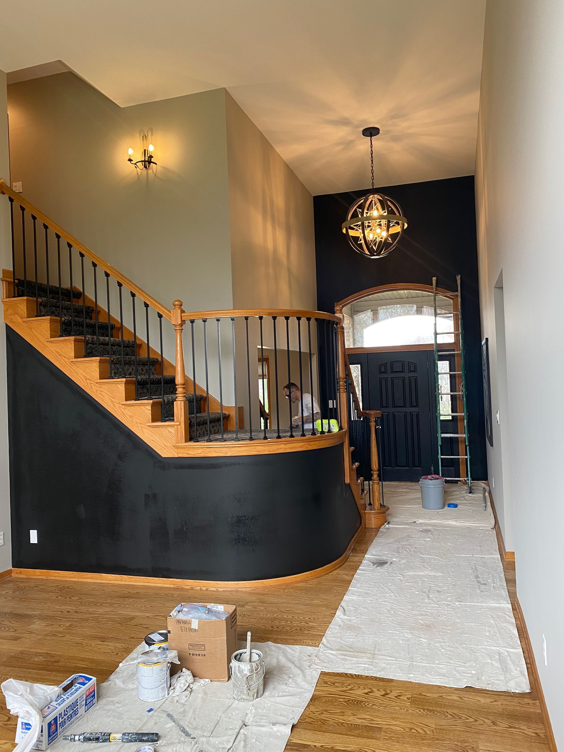 A living room with a staircase and a door being painted.