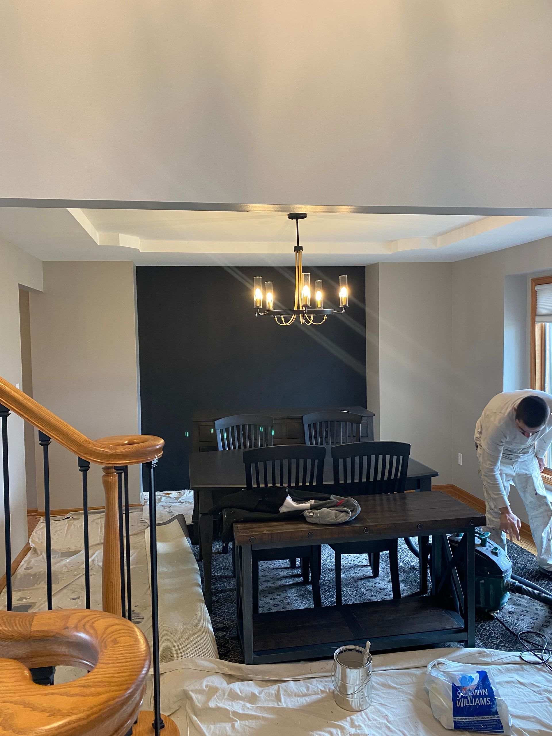 A man is painting a dining room in a house.