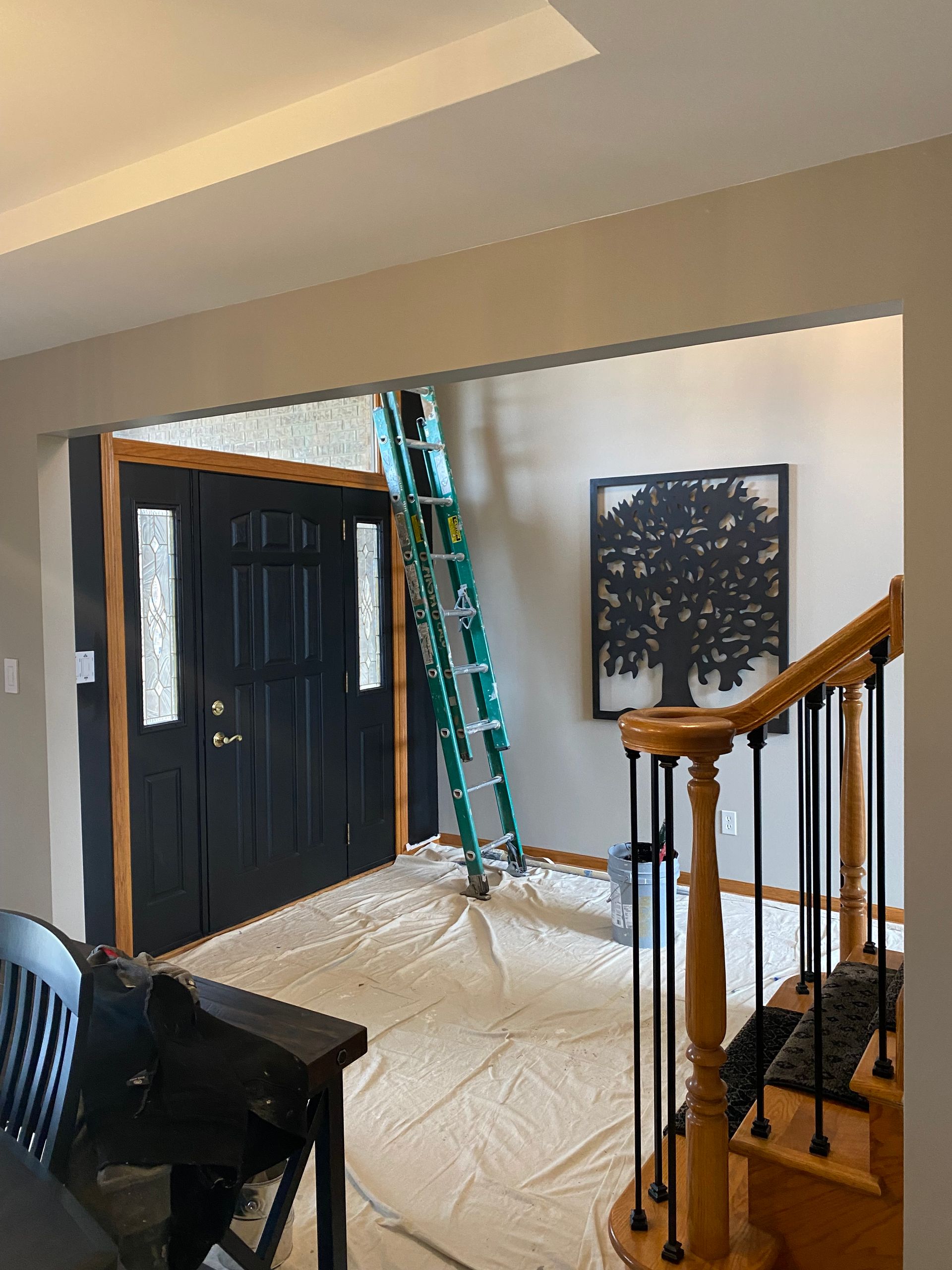 A living room with a table , chairs , stairs and a ladder.
