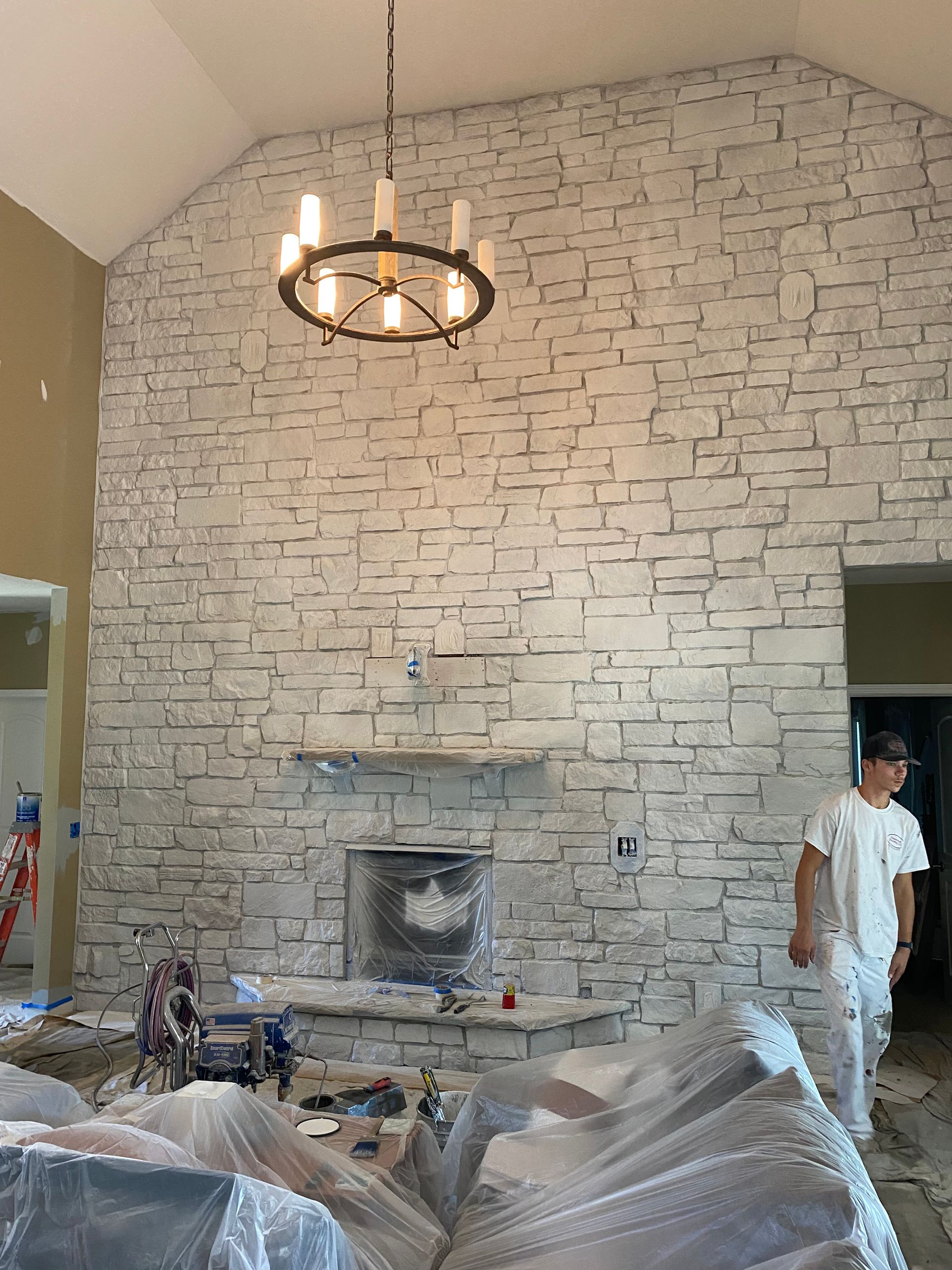 A man is standing in front of a white brick wall in a living room.