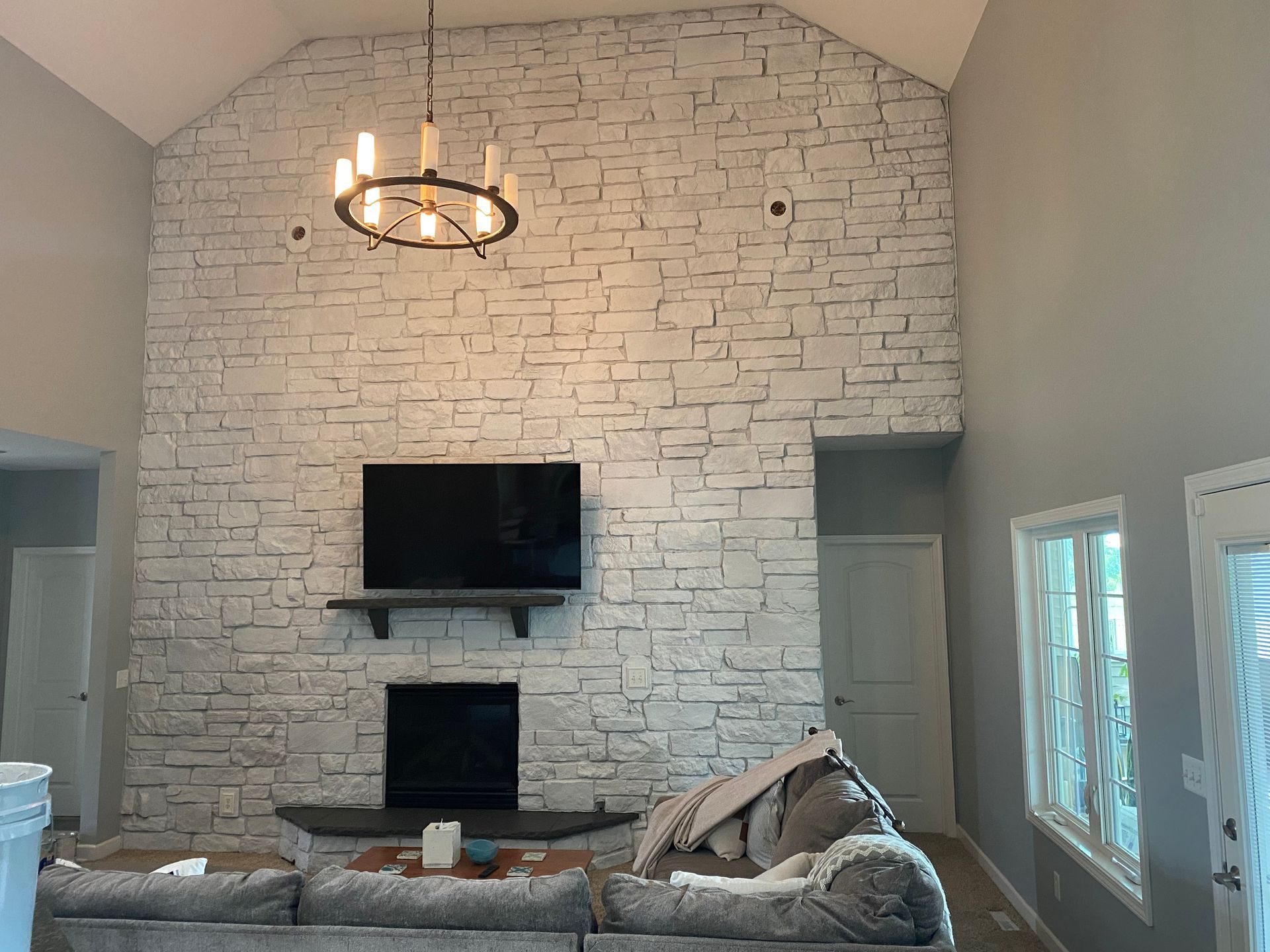 A living room with a fireplace , couch , television and chandelier.