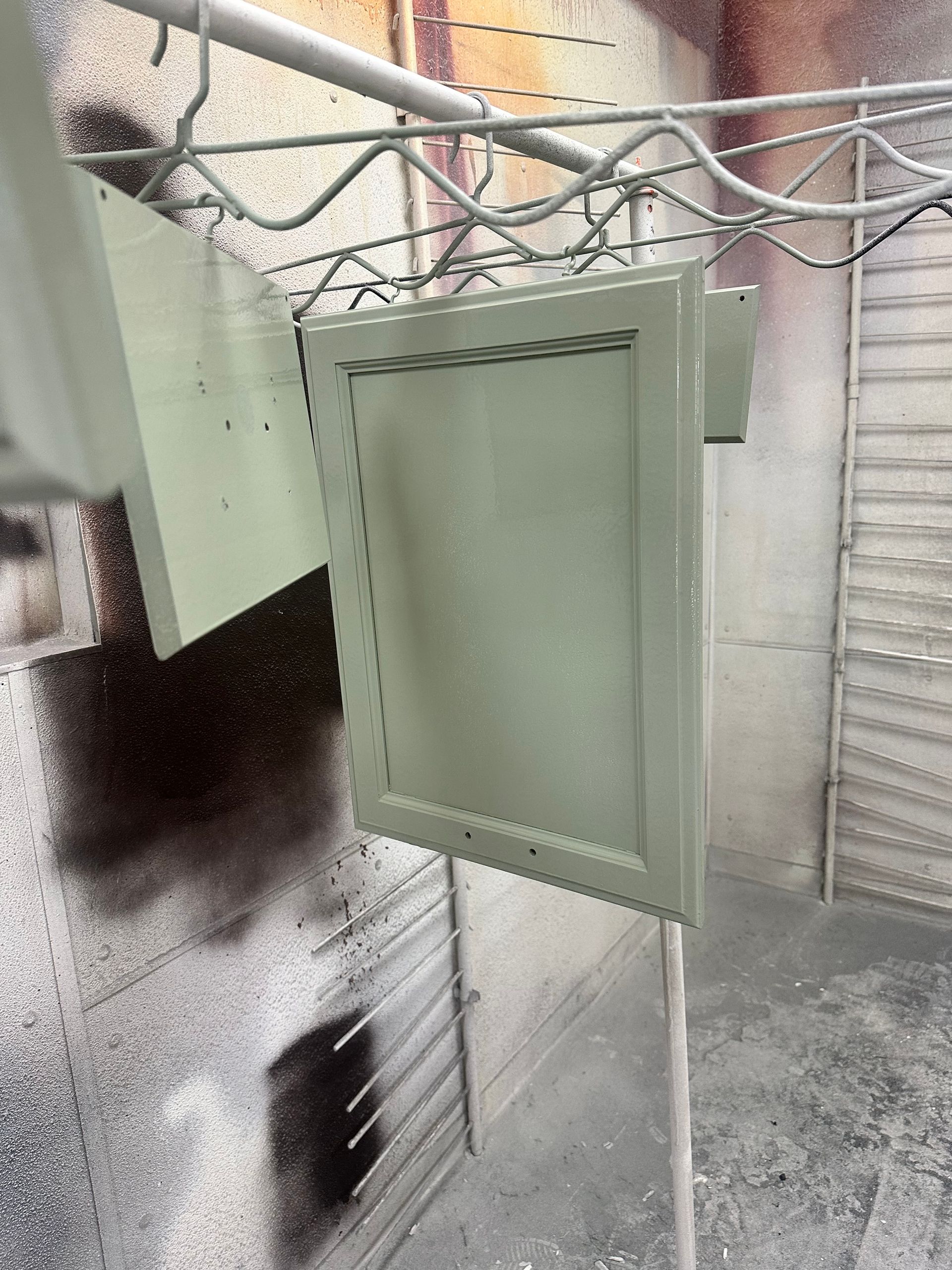 A green cabinet is hanging on a rack in a room.