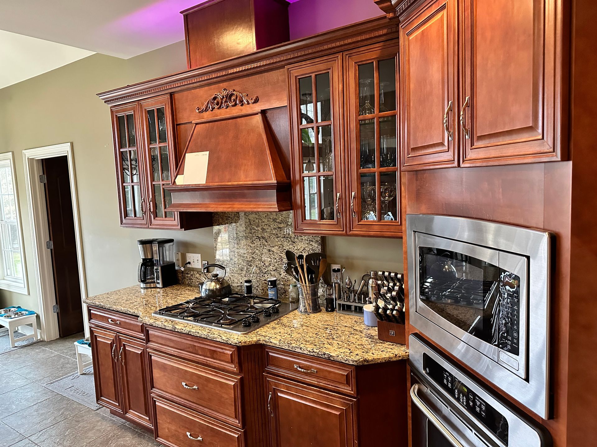 A kitchen with wooden cabinets , granite counter tops , stainless steel appliances and a stove.