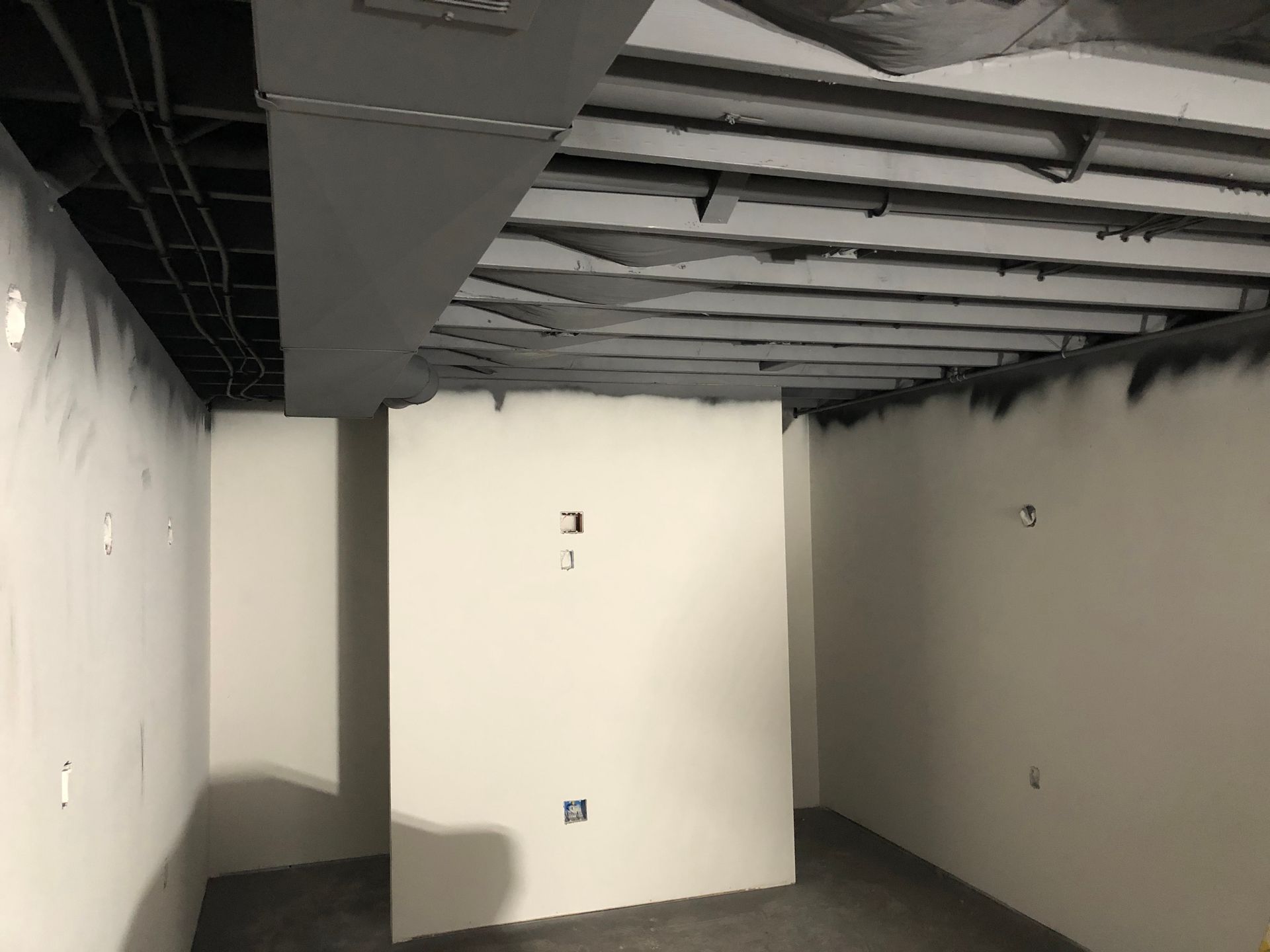 An empty room with white walls and a black ceiling.