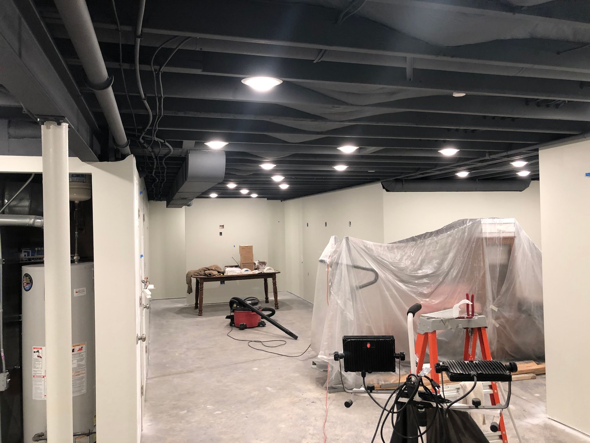 A basement under construction with a table and a vacuum cleaner.