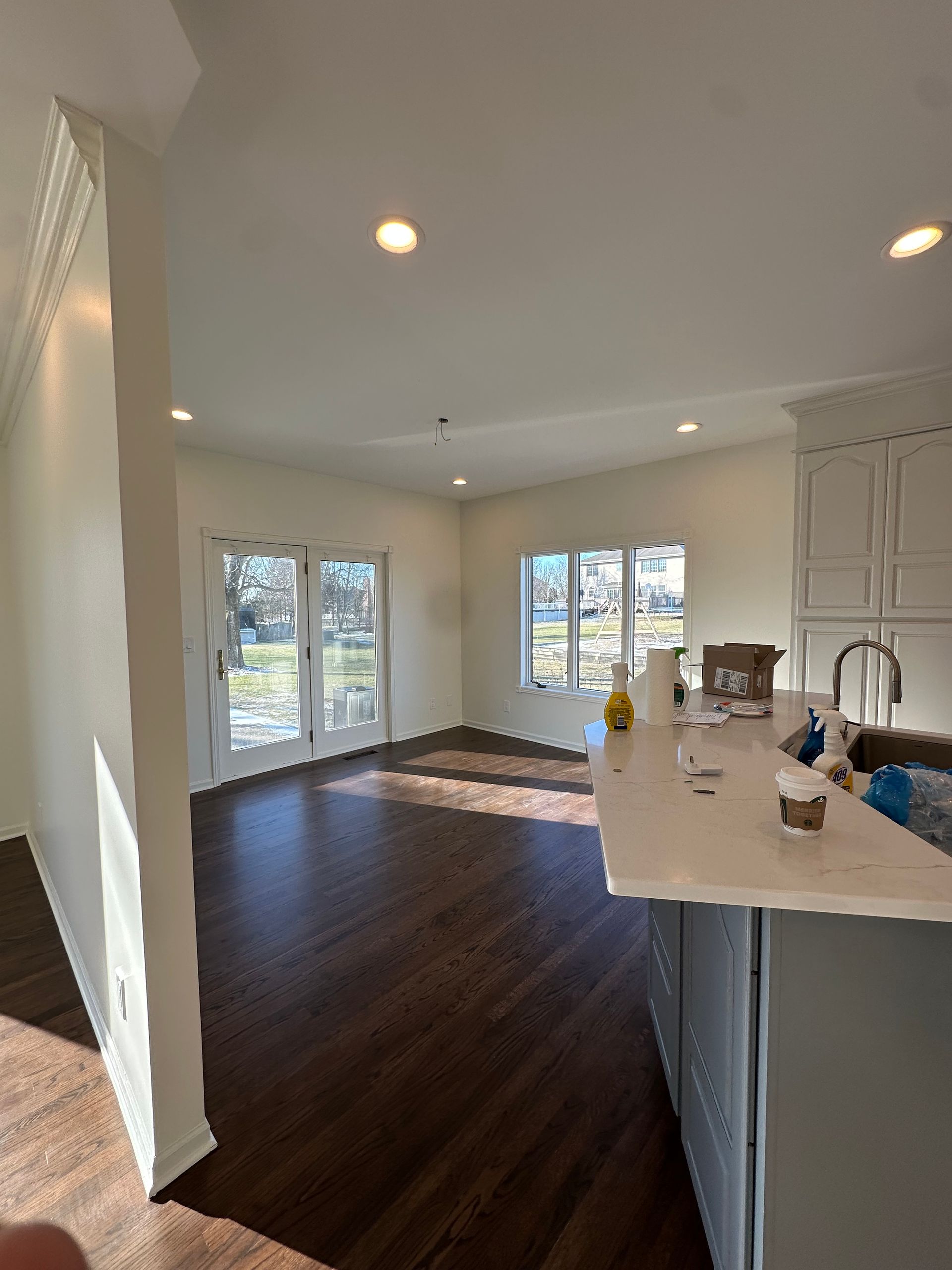 A kitchen with hardwood floors , white cabinets , and a large island.