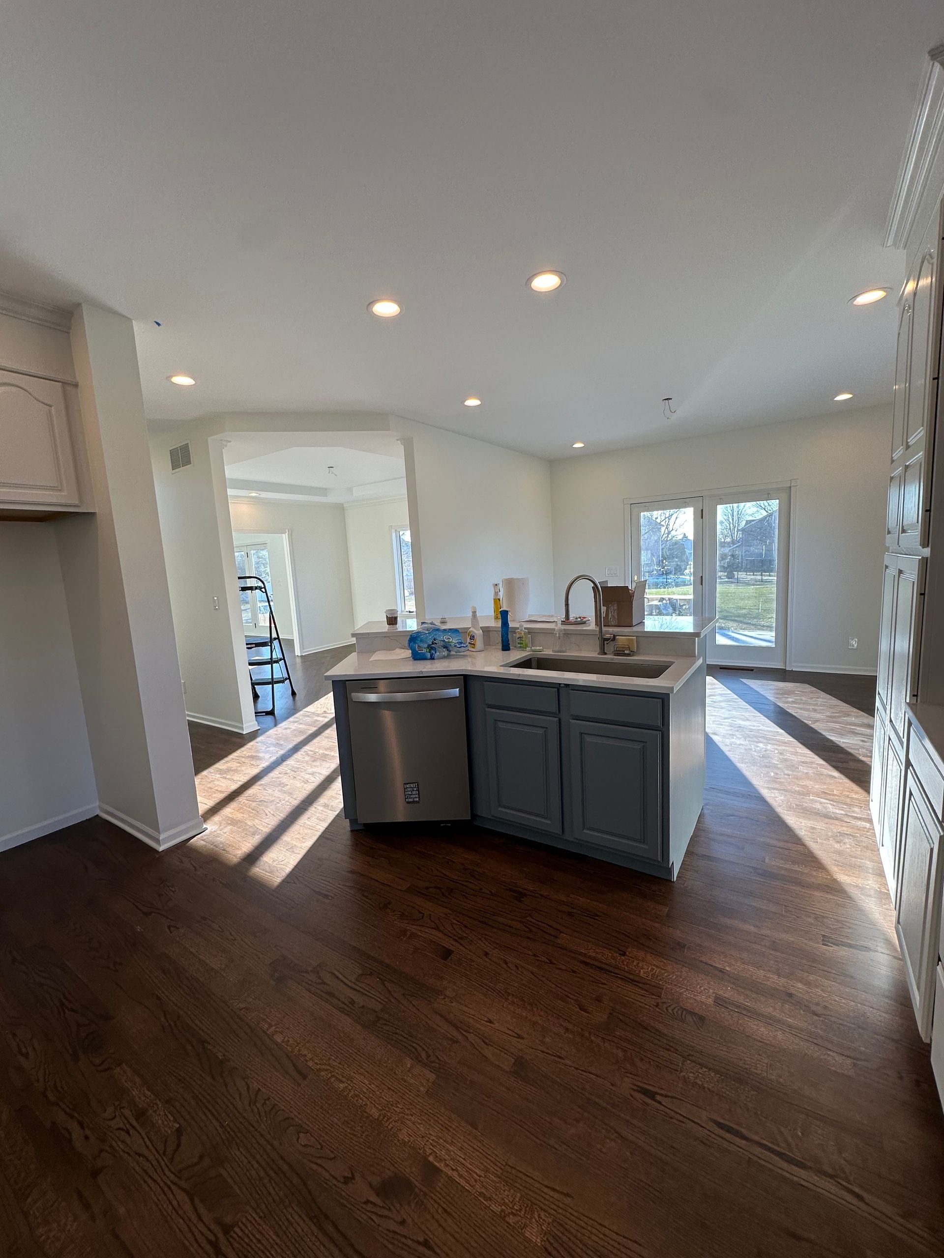 A kitchen with a large island , sink , dishwasher , and hardwood floors.