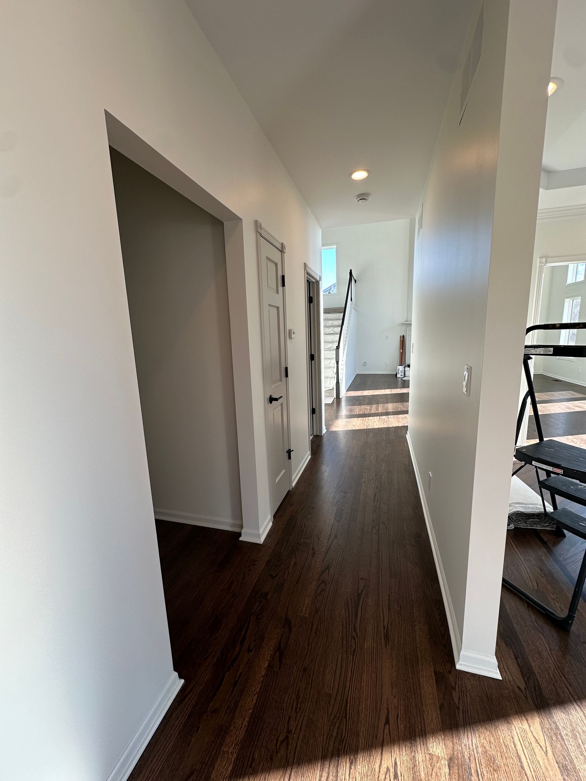 A long hallway with hardwood floors and white walls in a house.