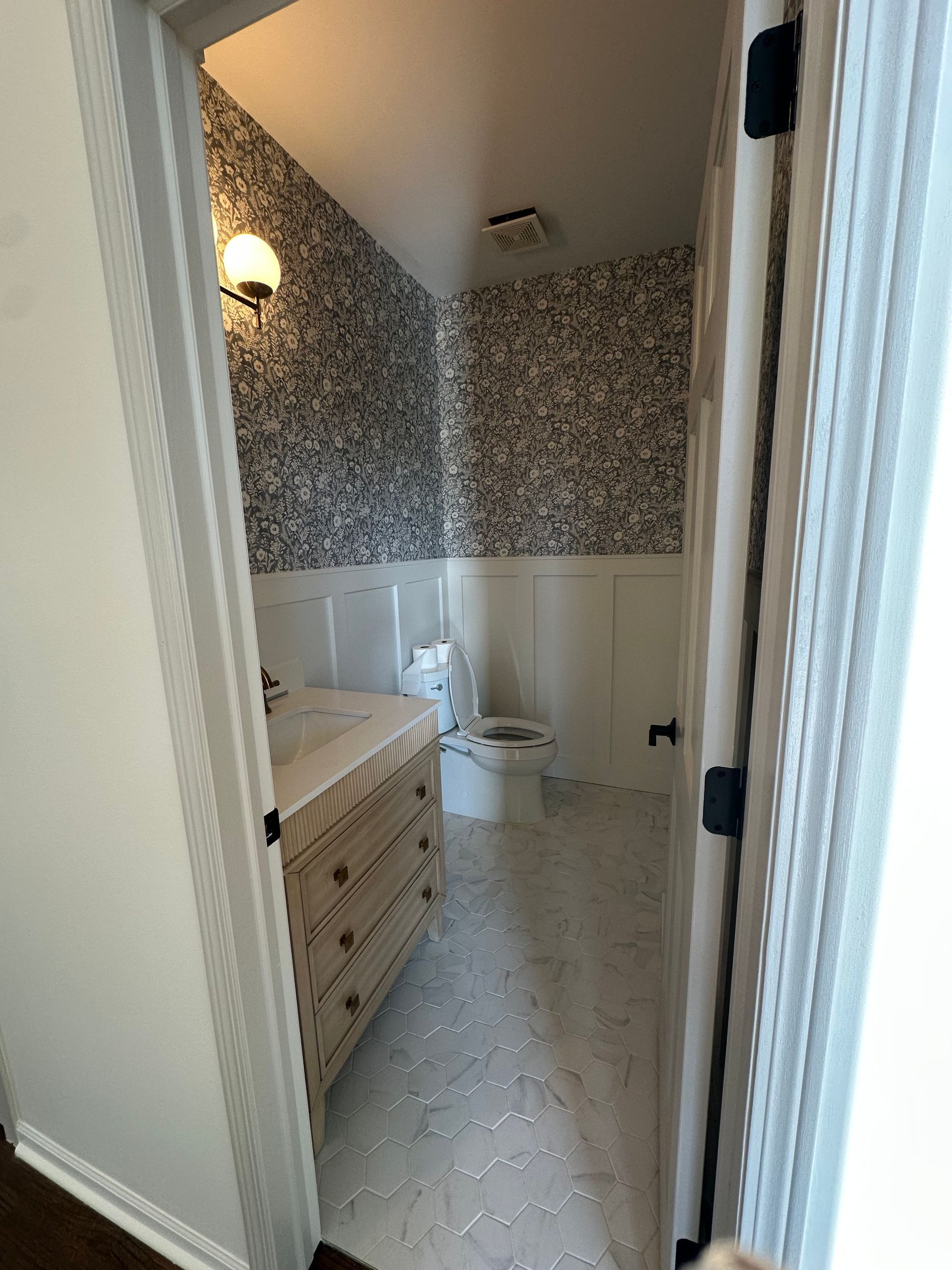 A bathroom with a toilet , sink and dresser.