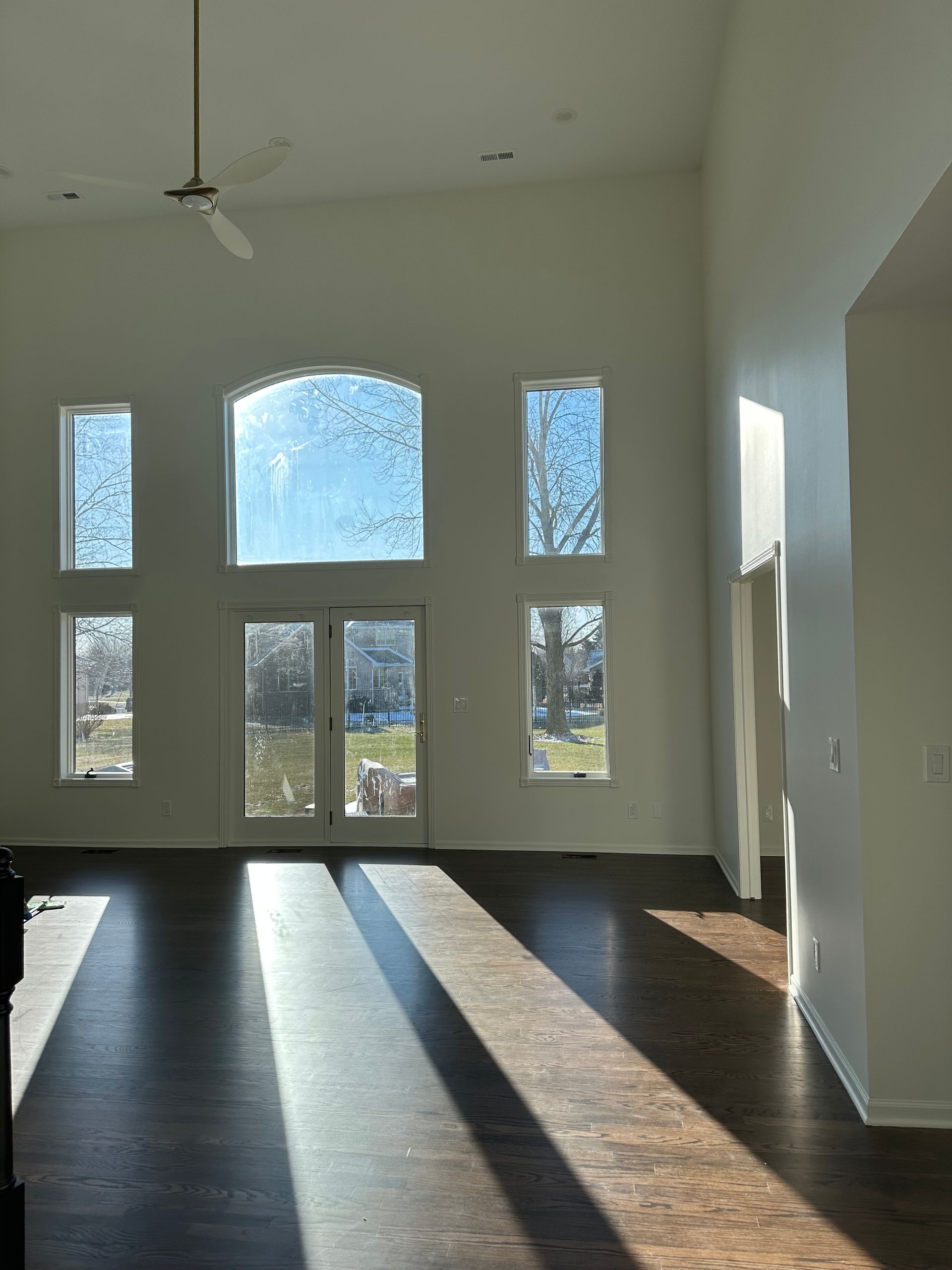 A large empty room with a lot of windows and a ceiling fan.