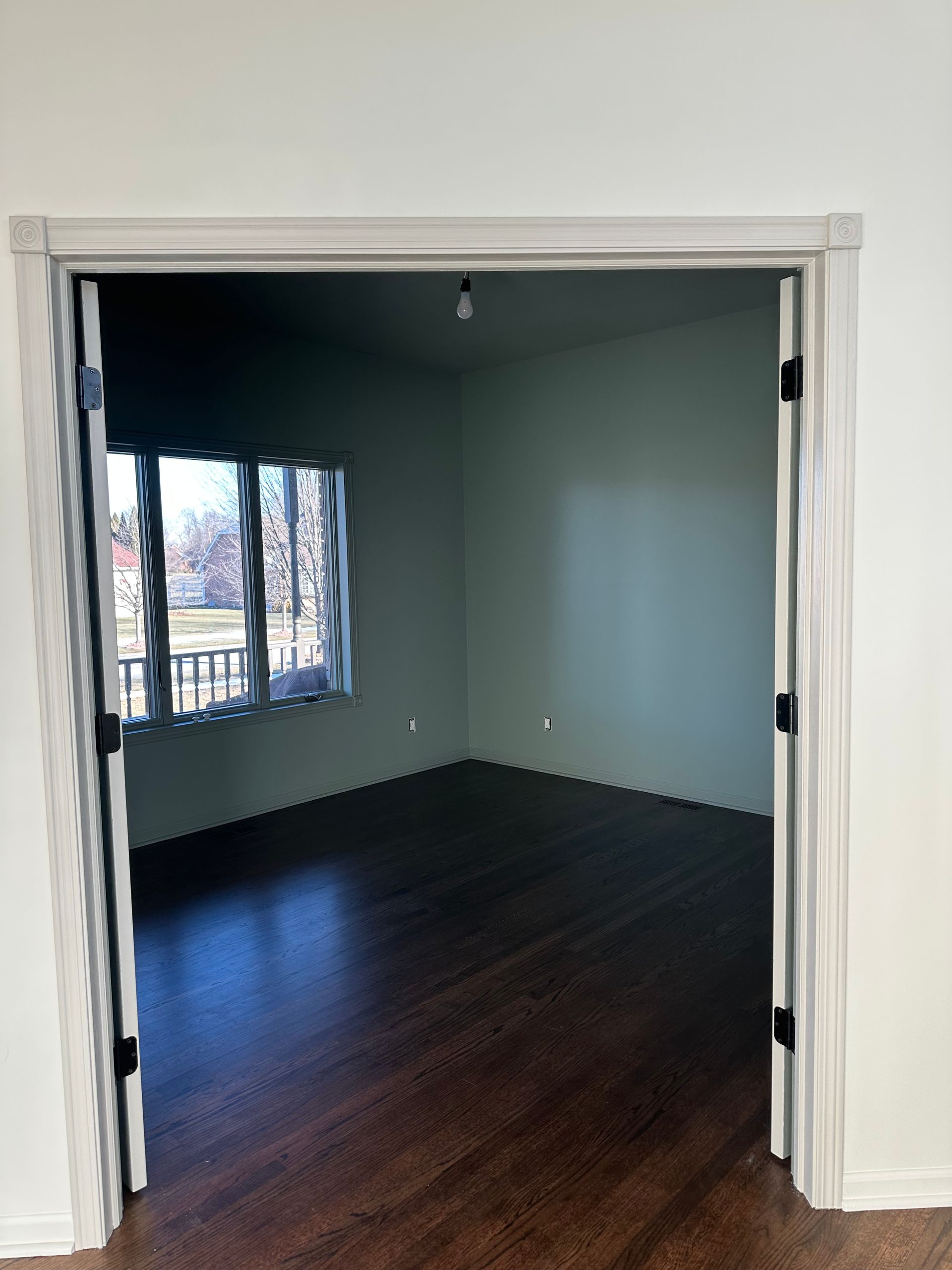 An empty room with hardwood floors and a window