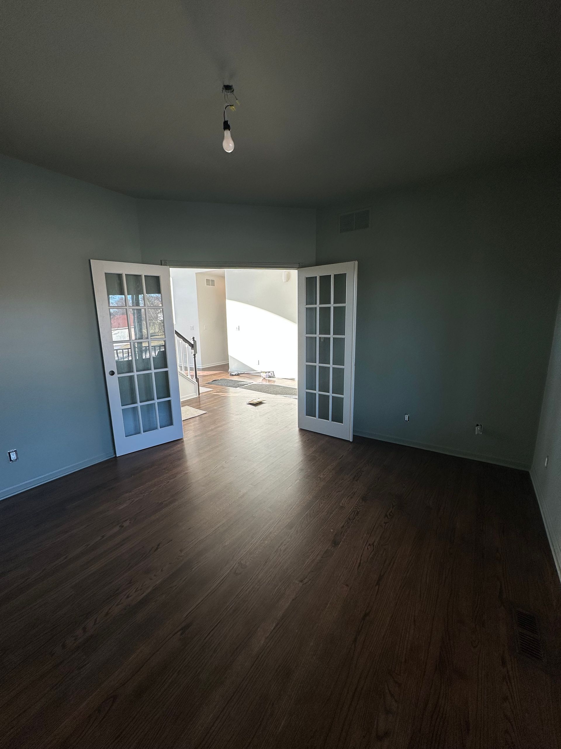 An empty living room with hardwood floors and french doors.