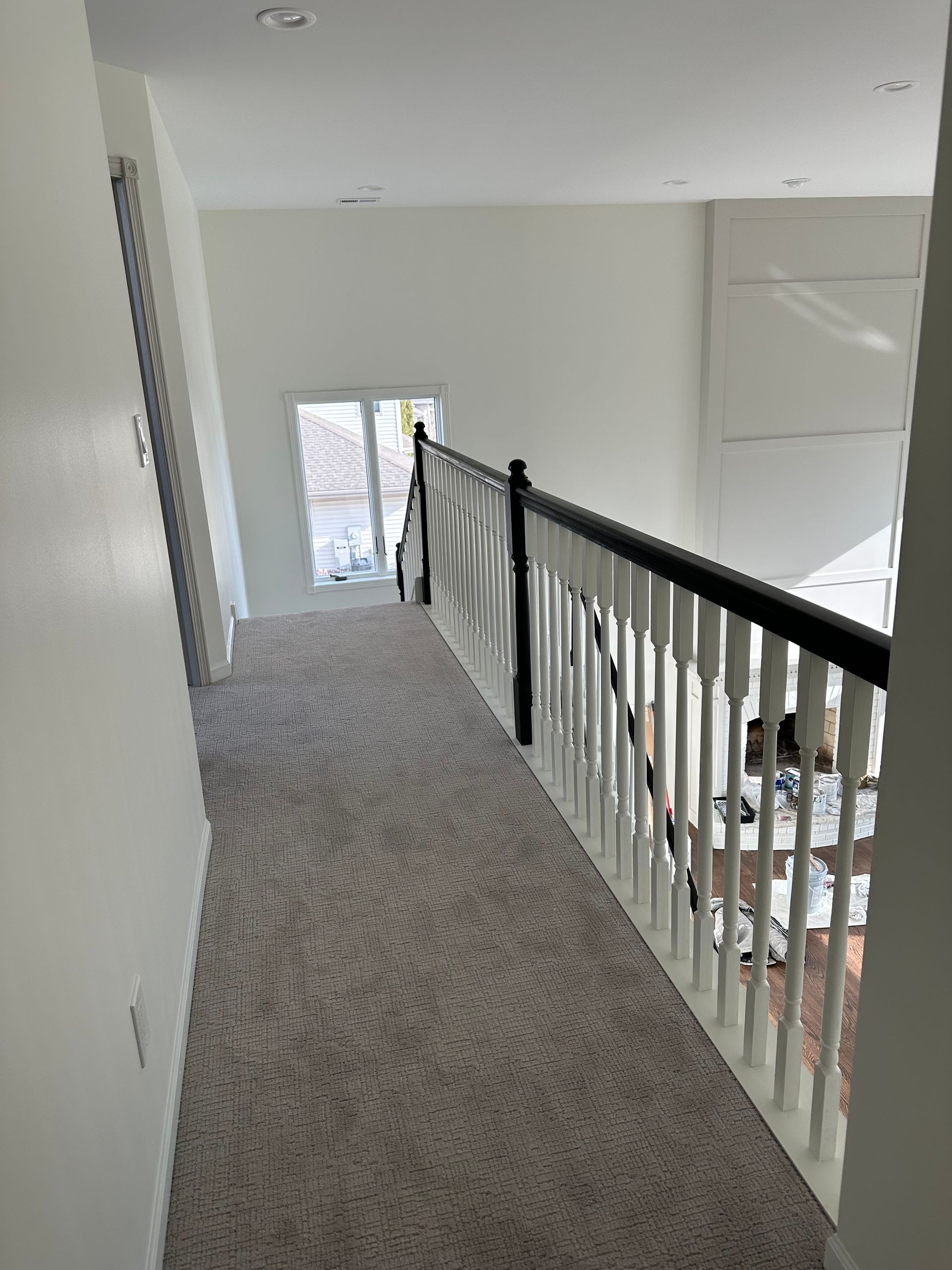 A hallway with a railing and stairs in a house.