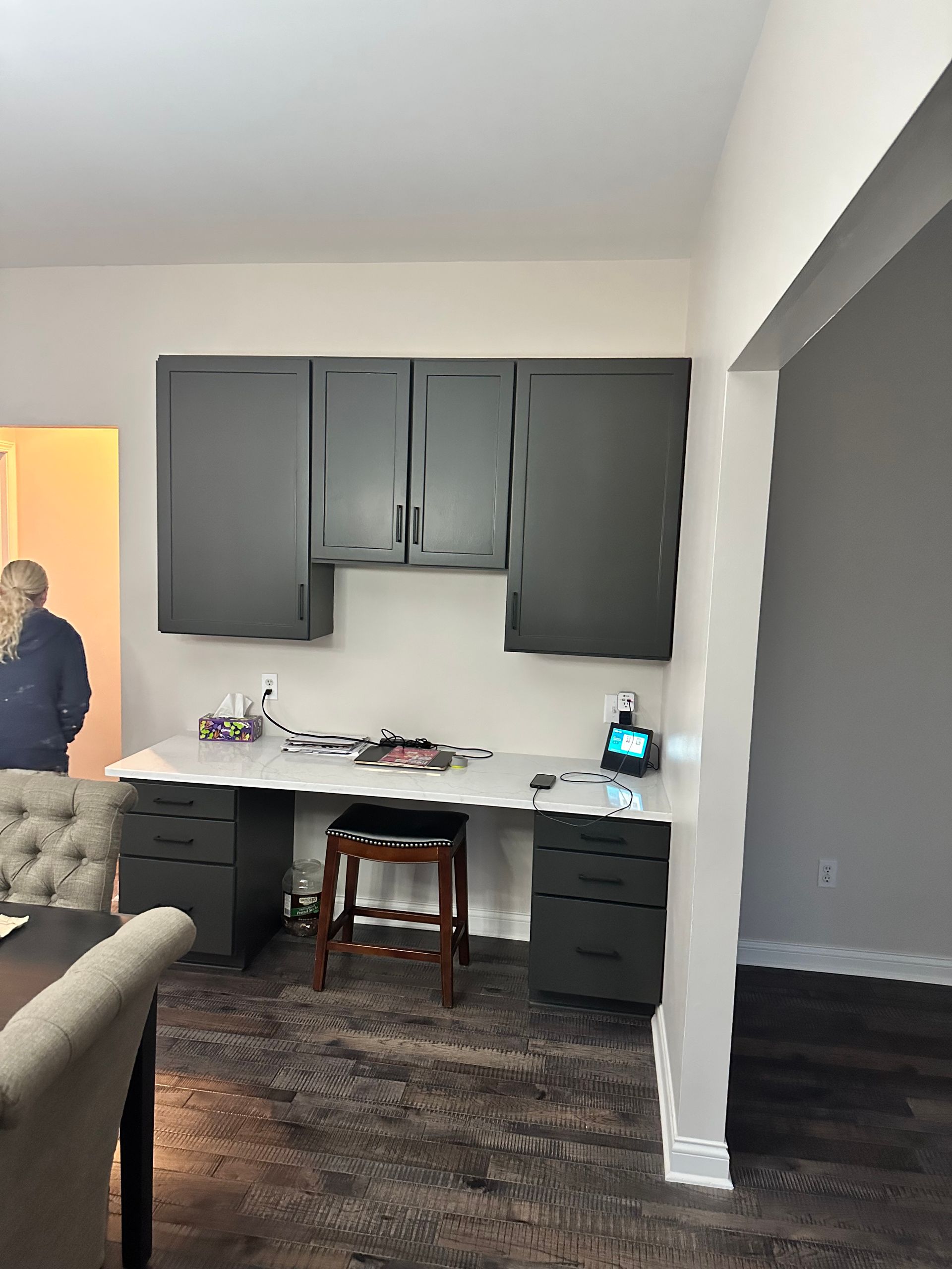 A man is standing in a room with a desk and cabinets.