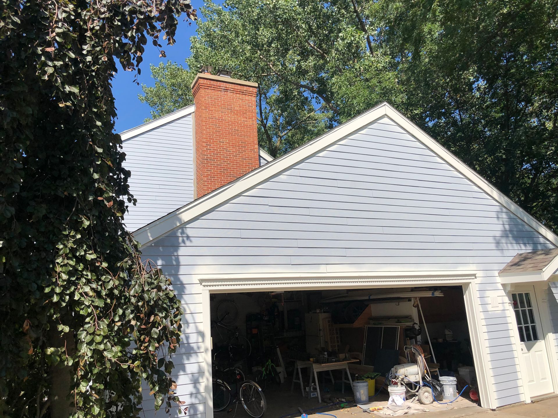 A house with a garage door open and a brick chimney.