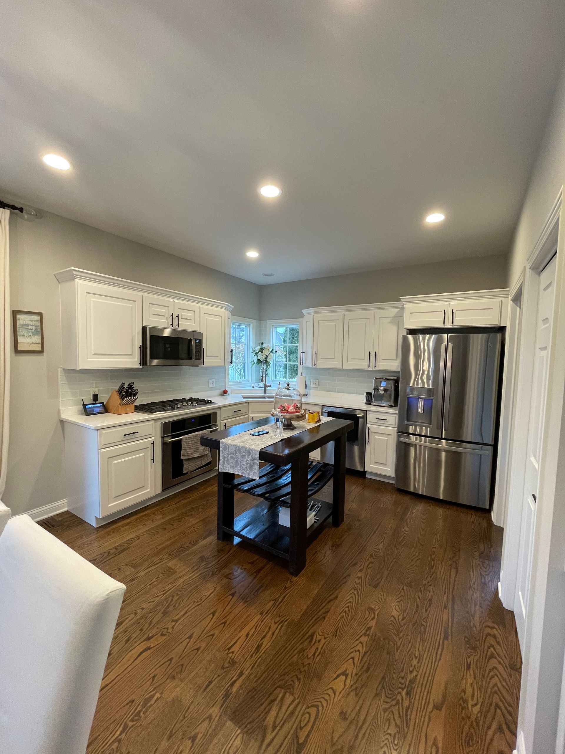 A kitchen with white cabinets , stainless steel appliances , and hardwood floors.