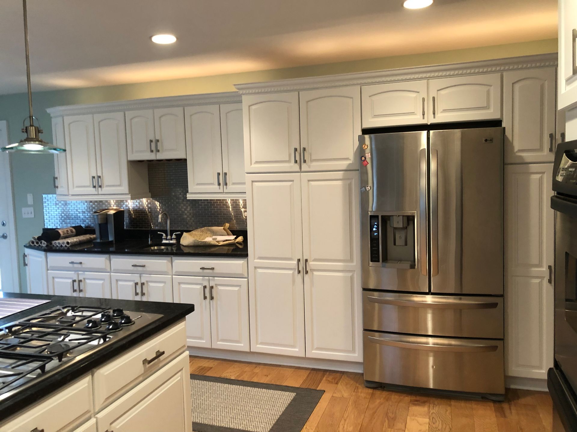 A kitchen with white cabinets and a stainless steel refrigerator