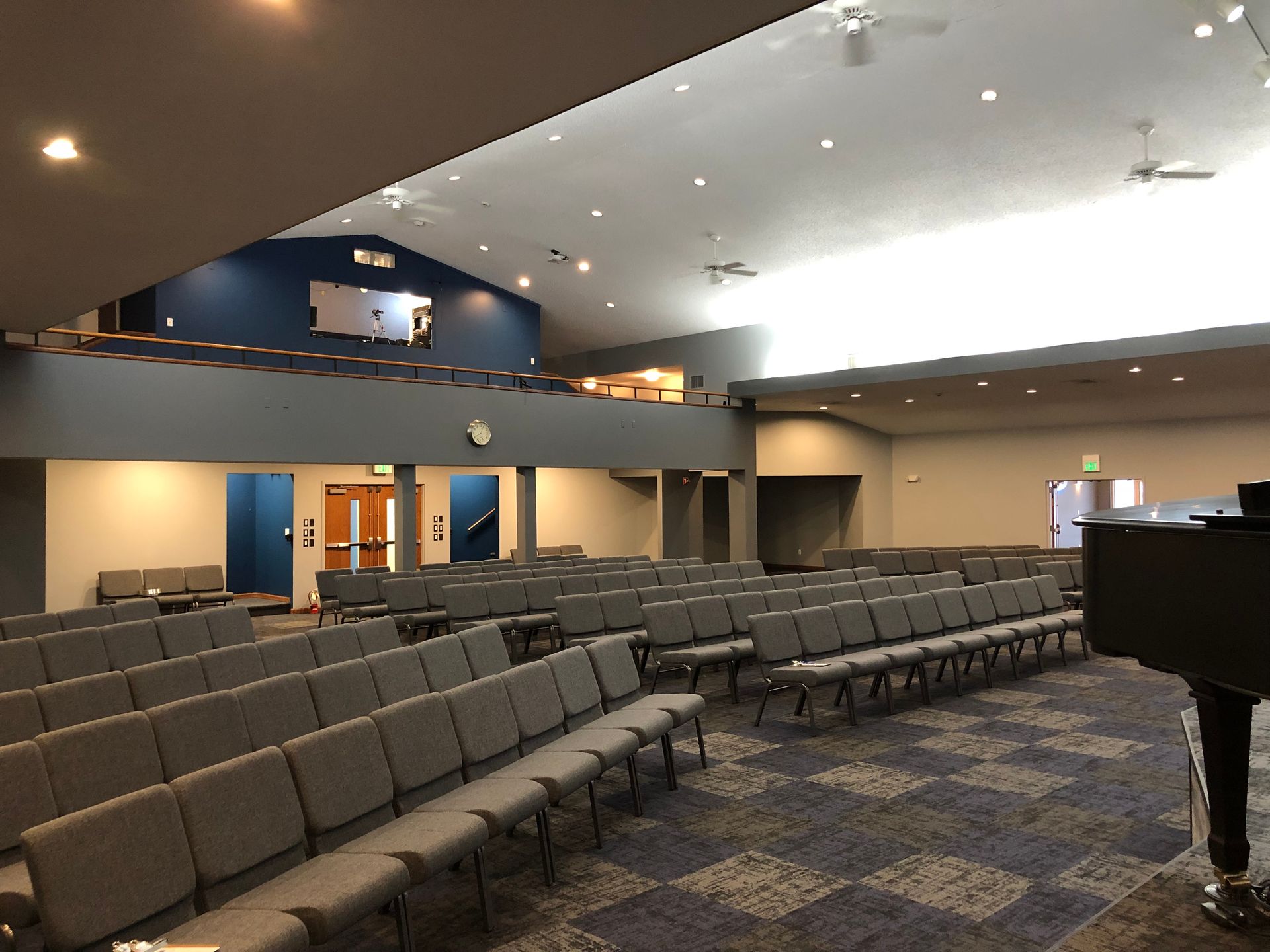A large auditorium with rows of chairs and a piano.