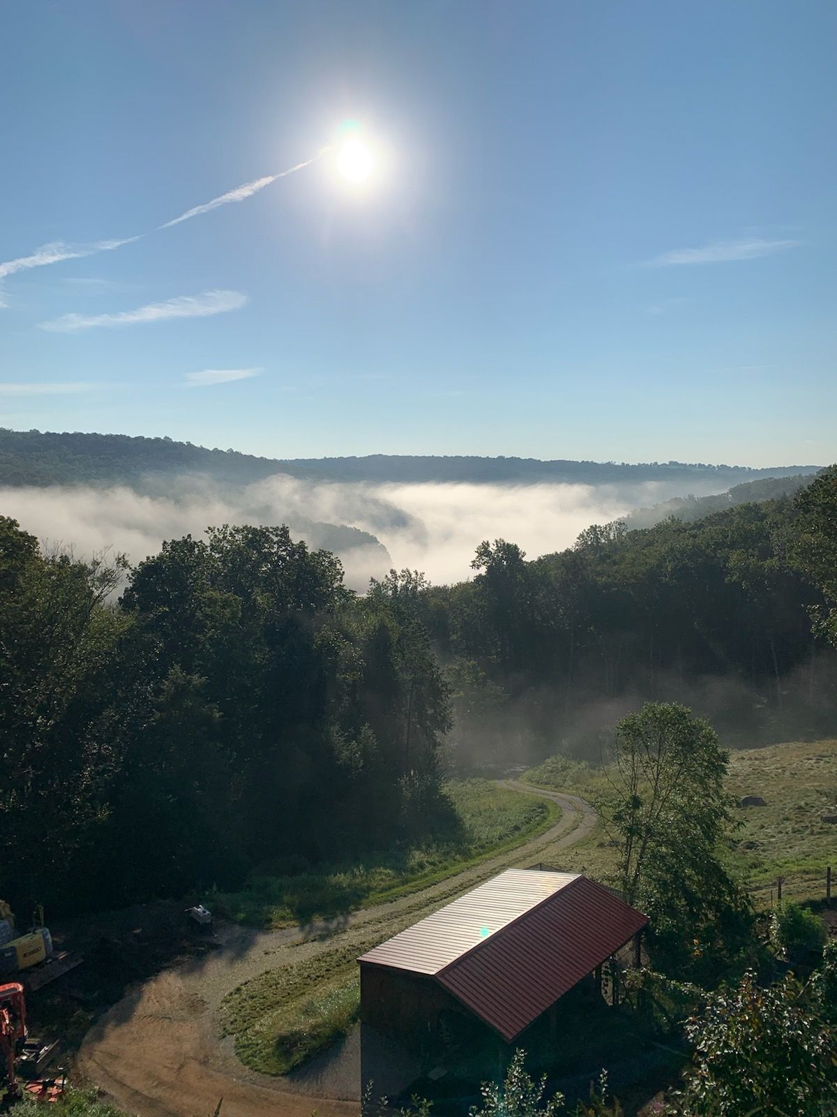 there is a barn in the middle of a field with a lot of fog in the background .