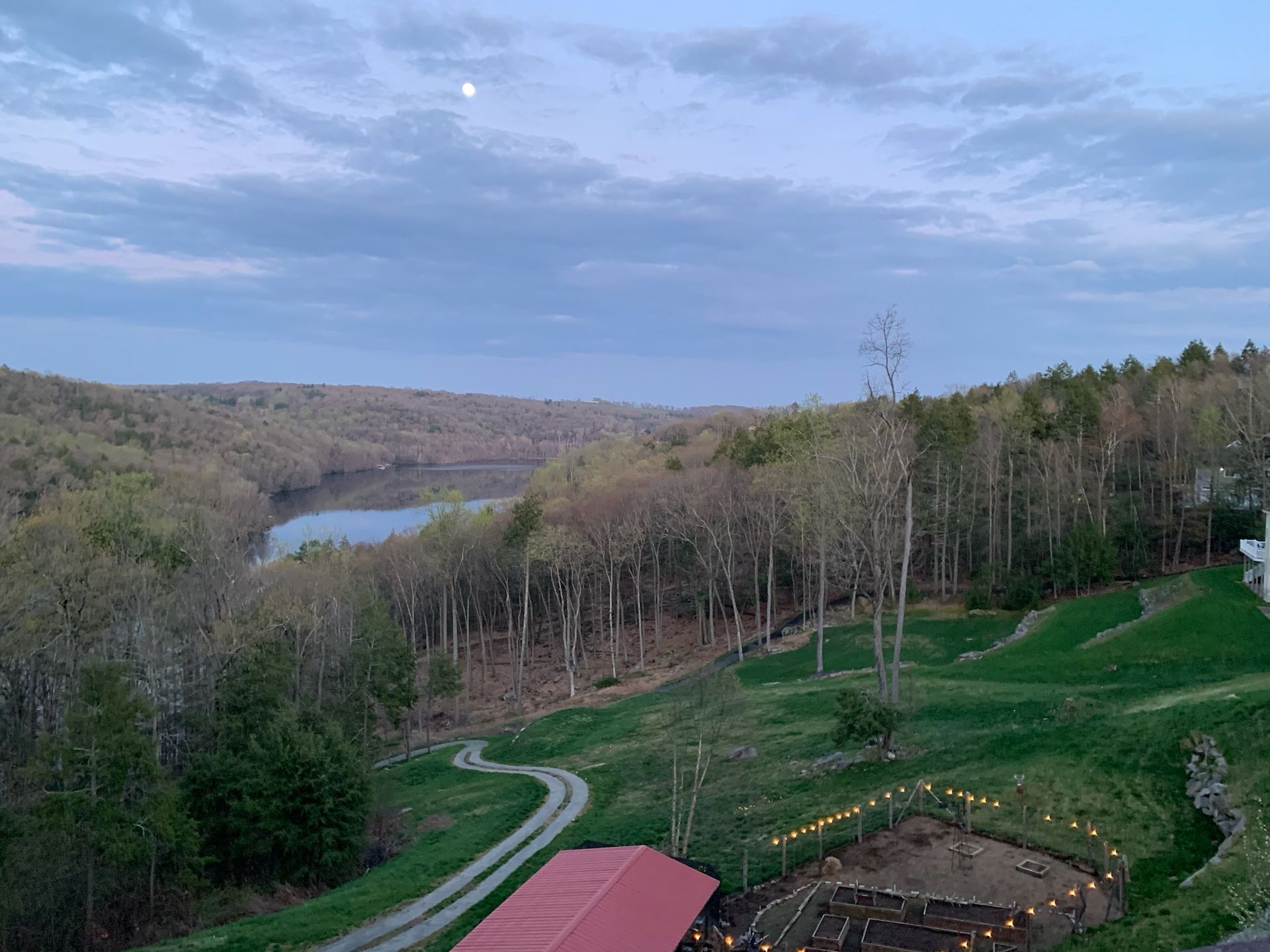 an aerial view of a farm with a red barn and a lake in the background