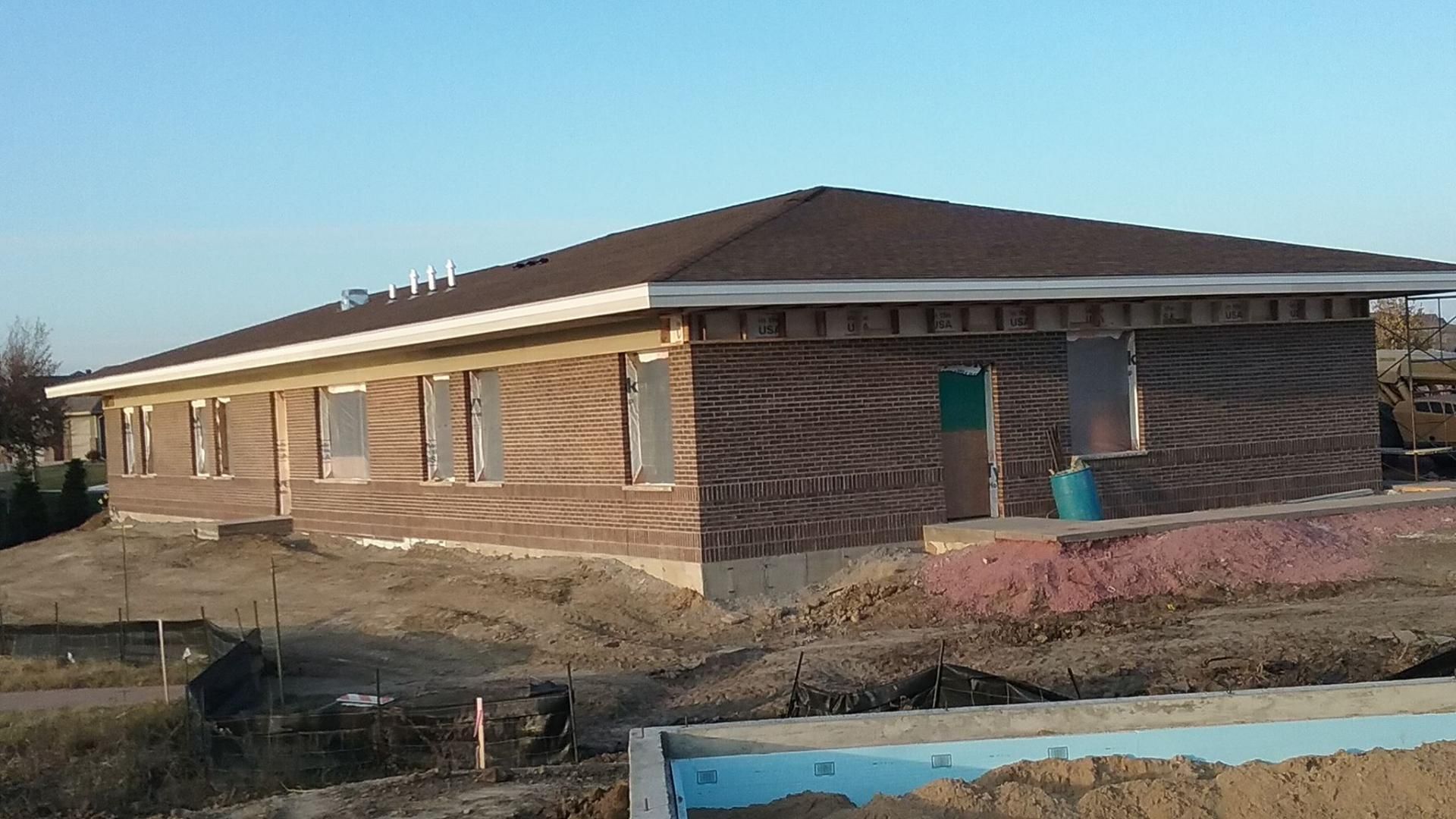 A brick house under construction with a brown roof