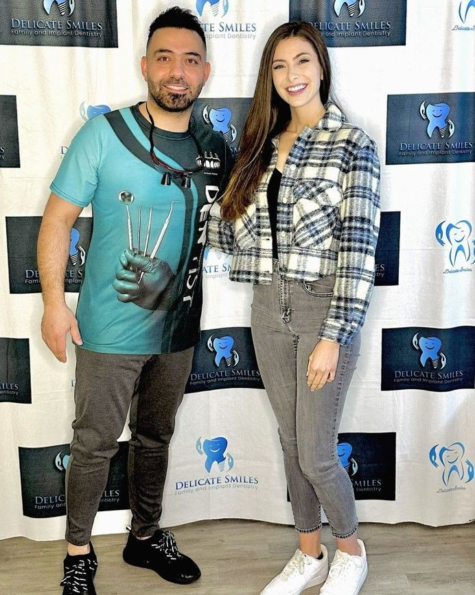 A man and a woman are standing next to each other in front of a backdrop.