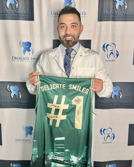 A man in a white coat and tie is holding a delicate smiles # 1 jersey.
