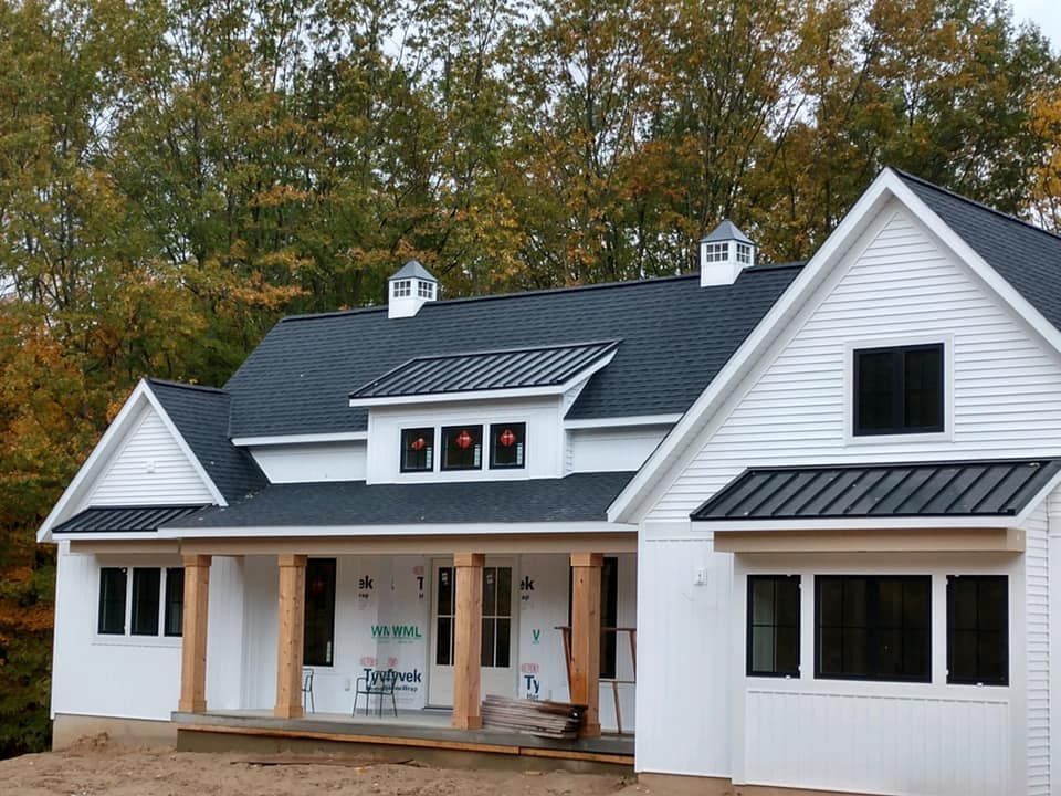 A white house with a black roof and a porch