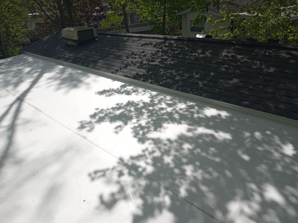 A white roof with a black roof and a tree shadow on it.
