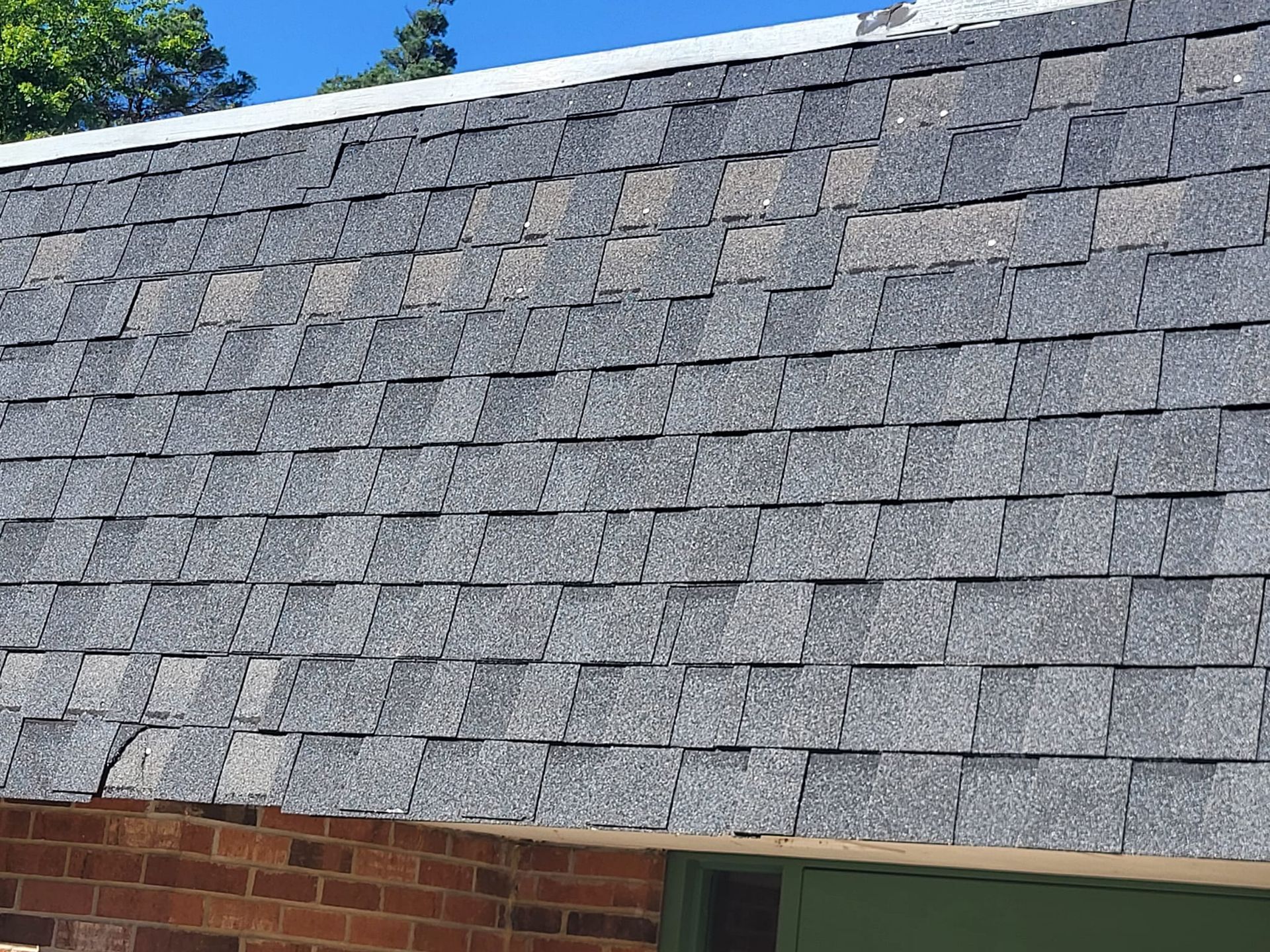 A close up of a roof with shingles on a brick building.