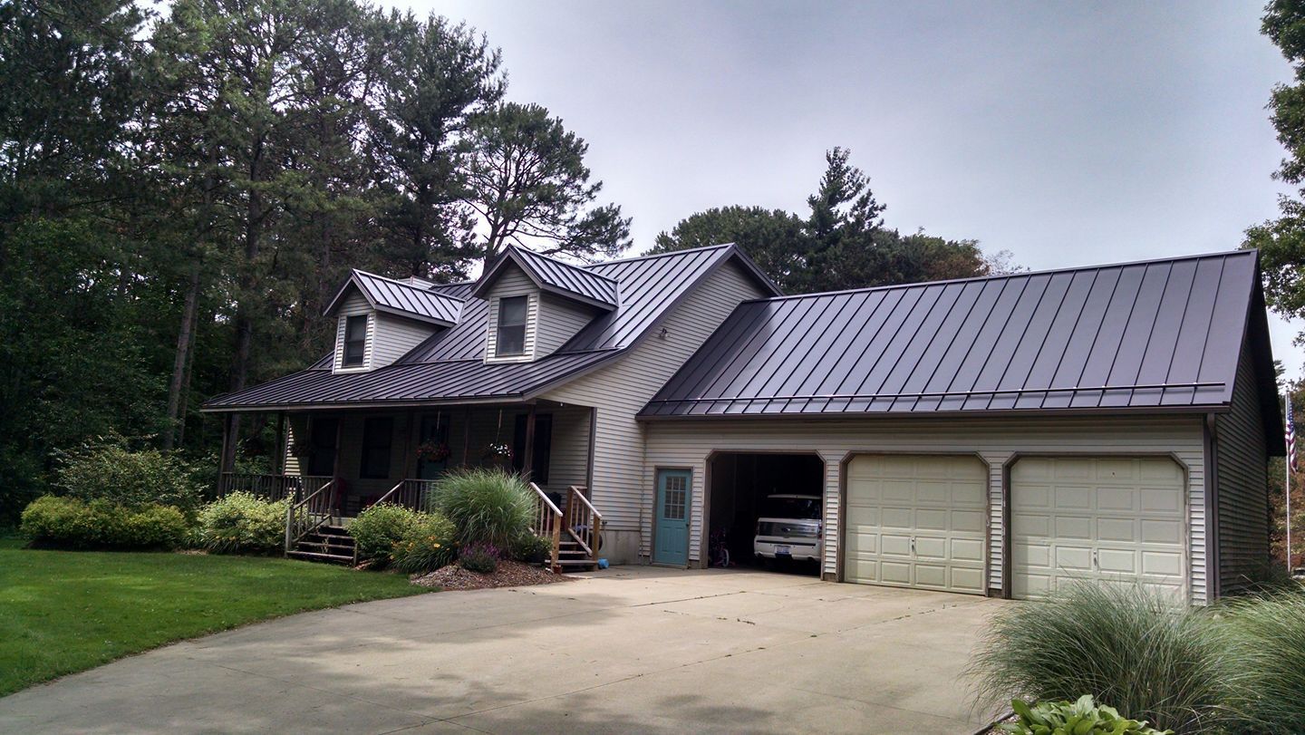 A house with a metal roof and a car parked in the driveway.
