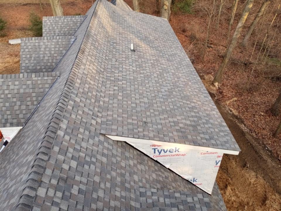An aerial view of a roof with shingles being installed.