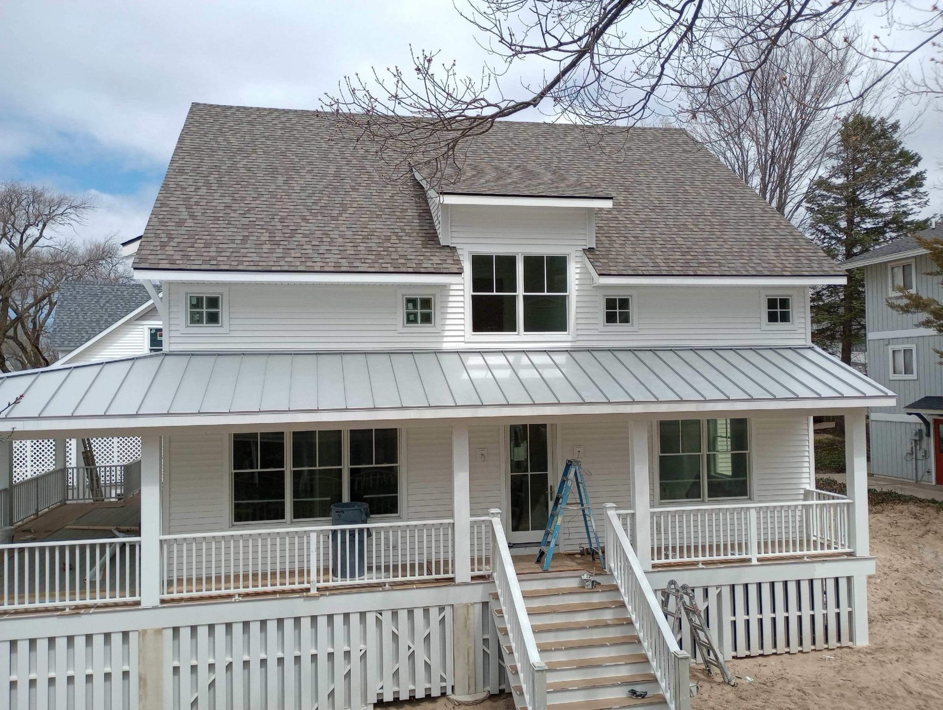 A white house with a metal roof and a large porch