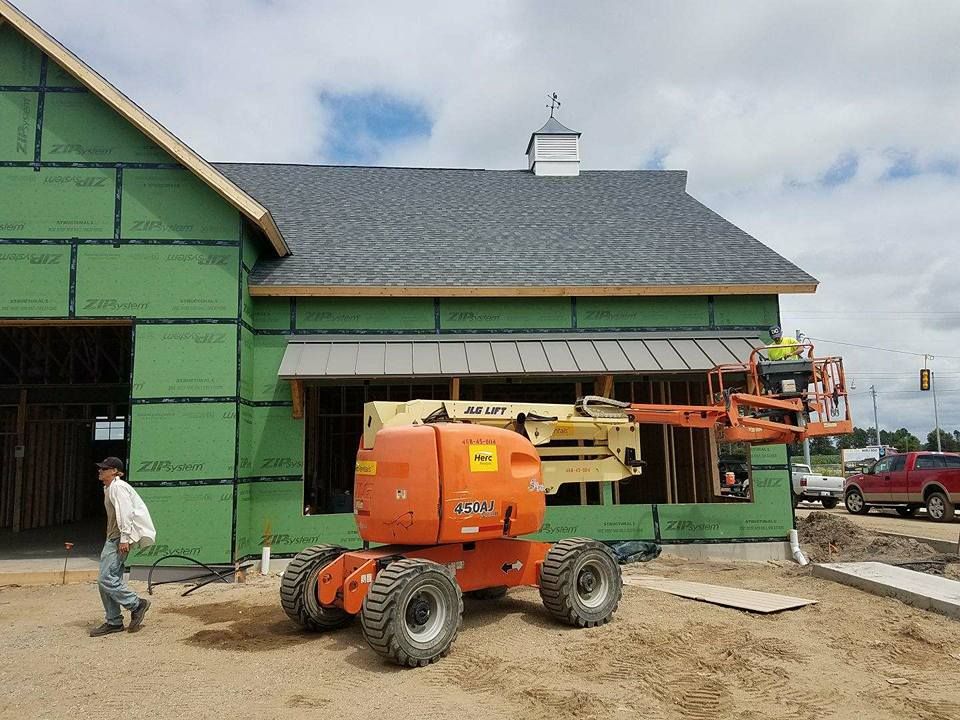 A construction vehicle is parked in front of a house under construction.