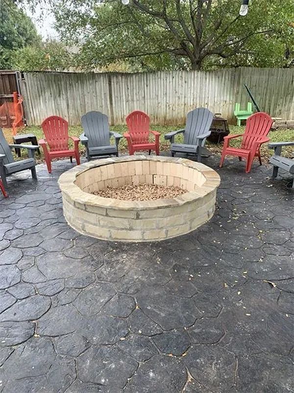 Backyard fire pit surrounded by colorful Adirondack chairs on a paved patio