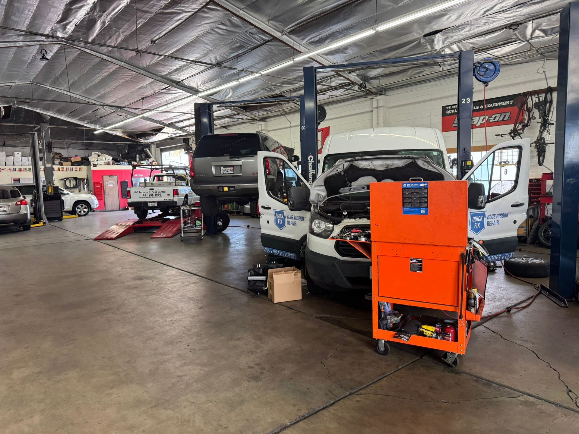 Auto repair shop with vehicles on lifts and an orange machine in the foreground