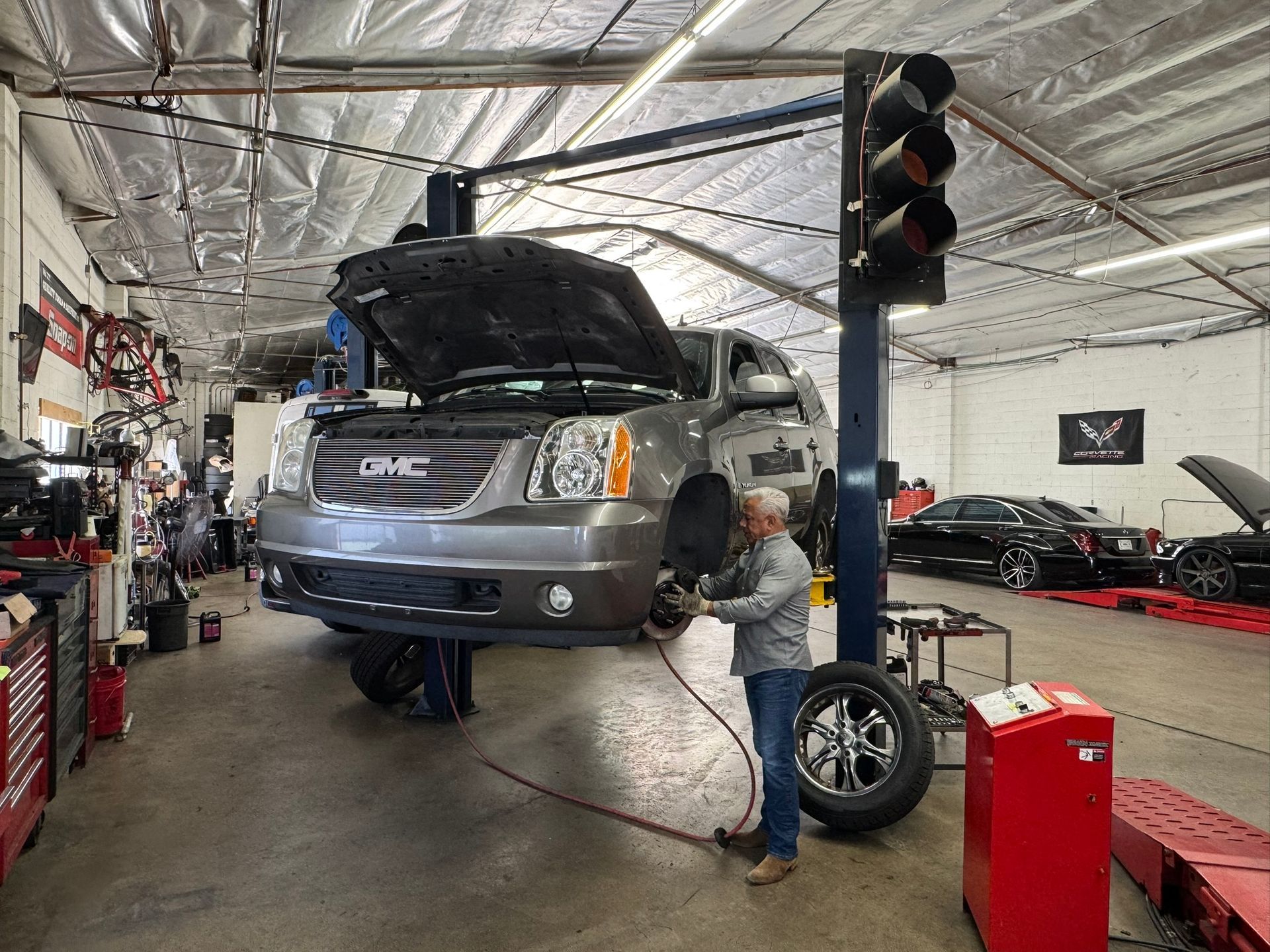 Mechanic working on a silver SUV with hood open in an auto repair shop