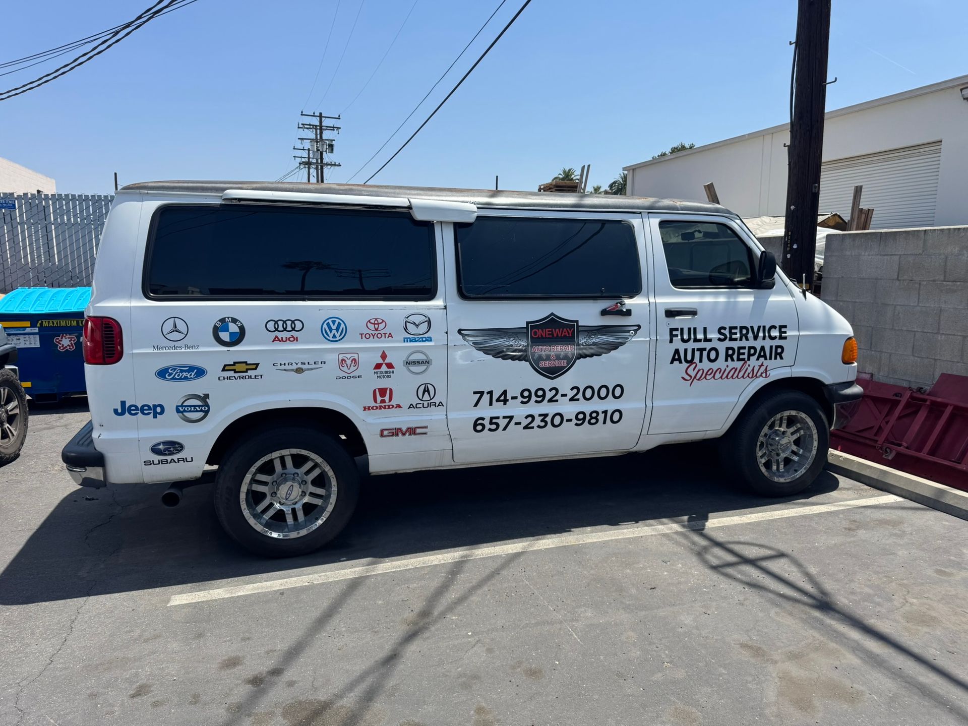 White service van with auto repair signage and logos parked outdoors in a lot
