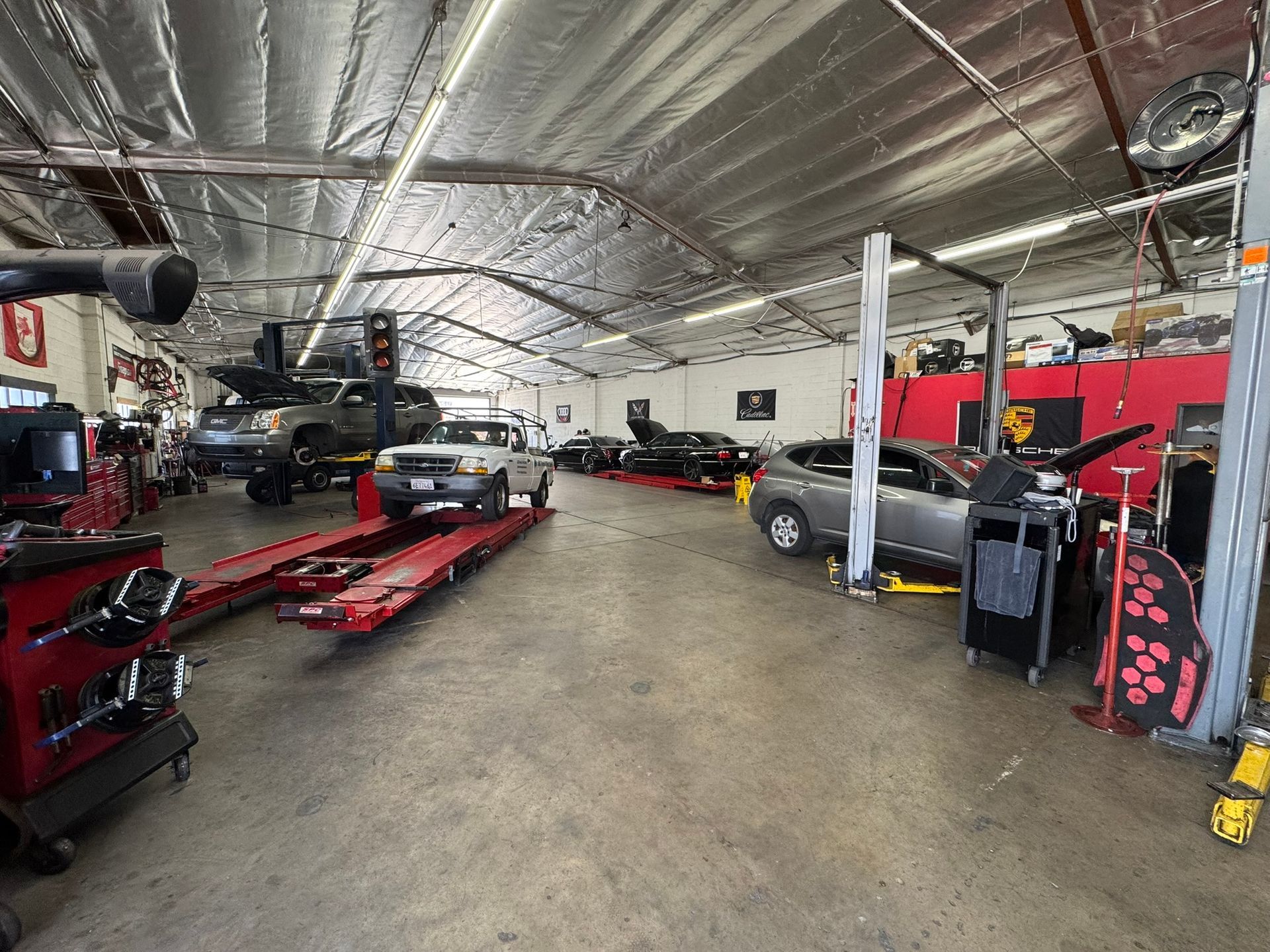 Auto repair shop with cars on lifts and a red alignment rack in a large garage