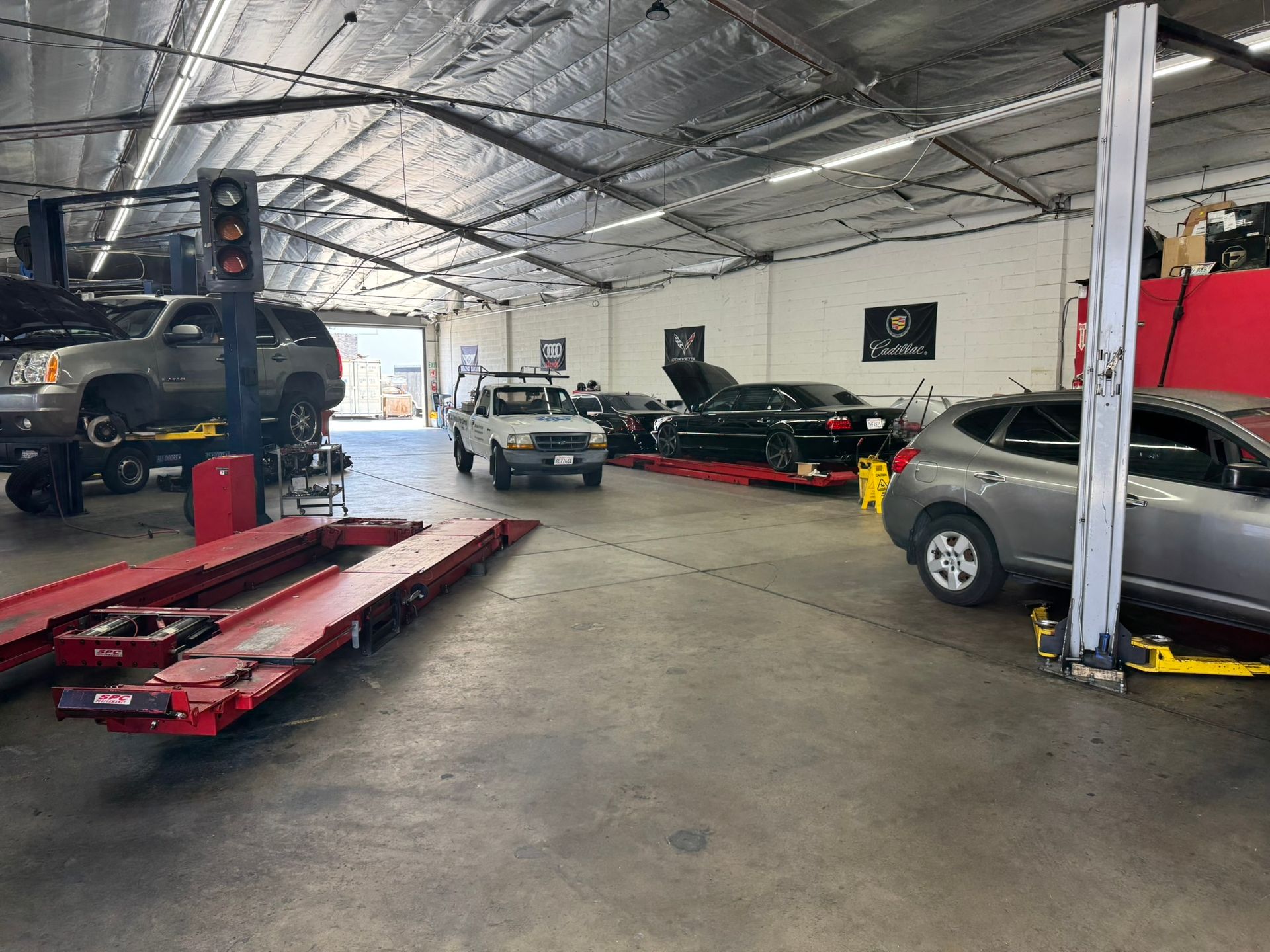 Auto repair shop with lifts, several vehicles, and a red alignment rack on the floor