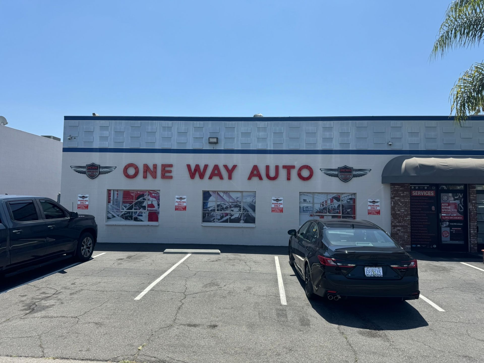 One Way Auto storefront with parked cars in a sunny lot