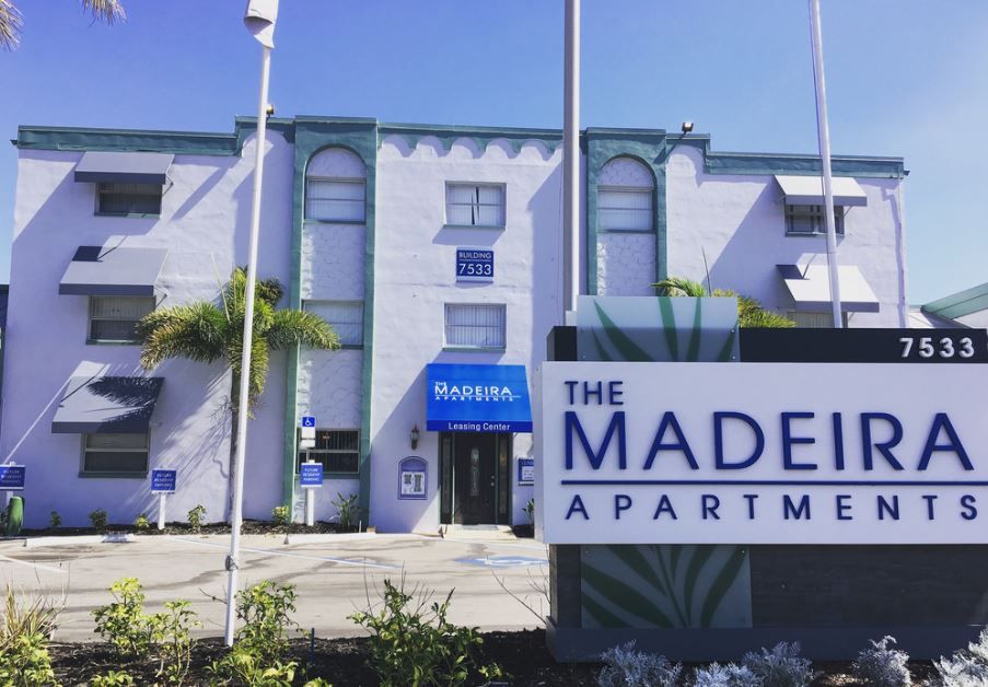 A white building with a sign that says the madeira apartments
