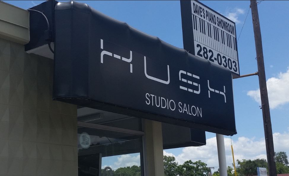 A black awning over a building that says hush studio salon