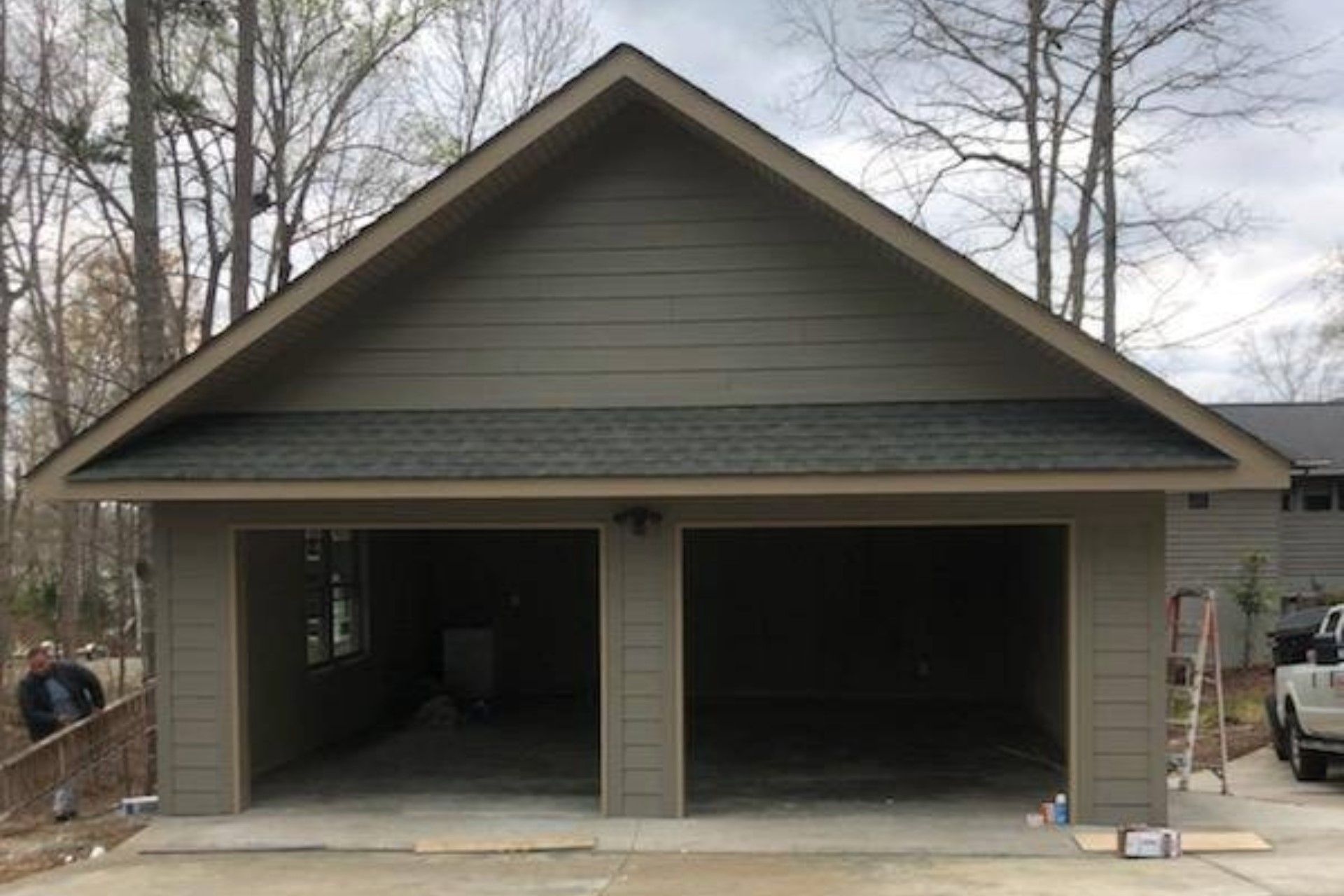 A garage with two doors and a truck parked in front of it.