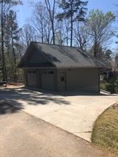 A garage with a driveway and trees in the background.
