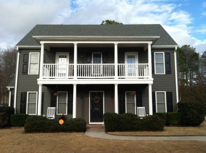 A large gray house with white shutters and a balcony