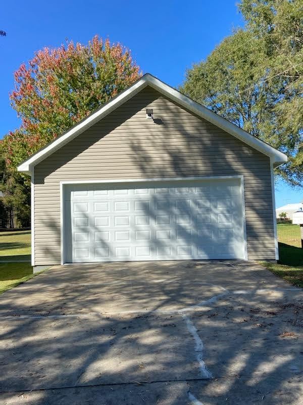 A garage with a white door and a tree in the background