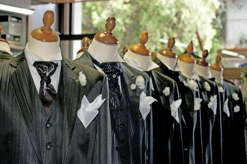 A row of men 's suits are lined up on mannequins