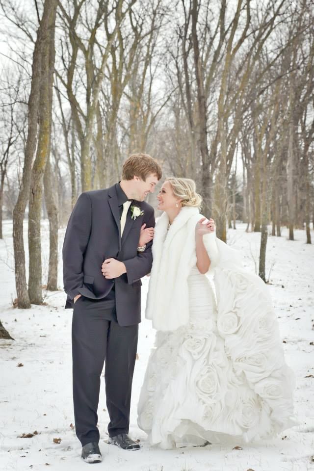 A bride and groom are kissing in the snow.